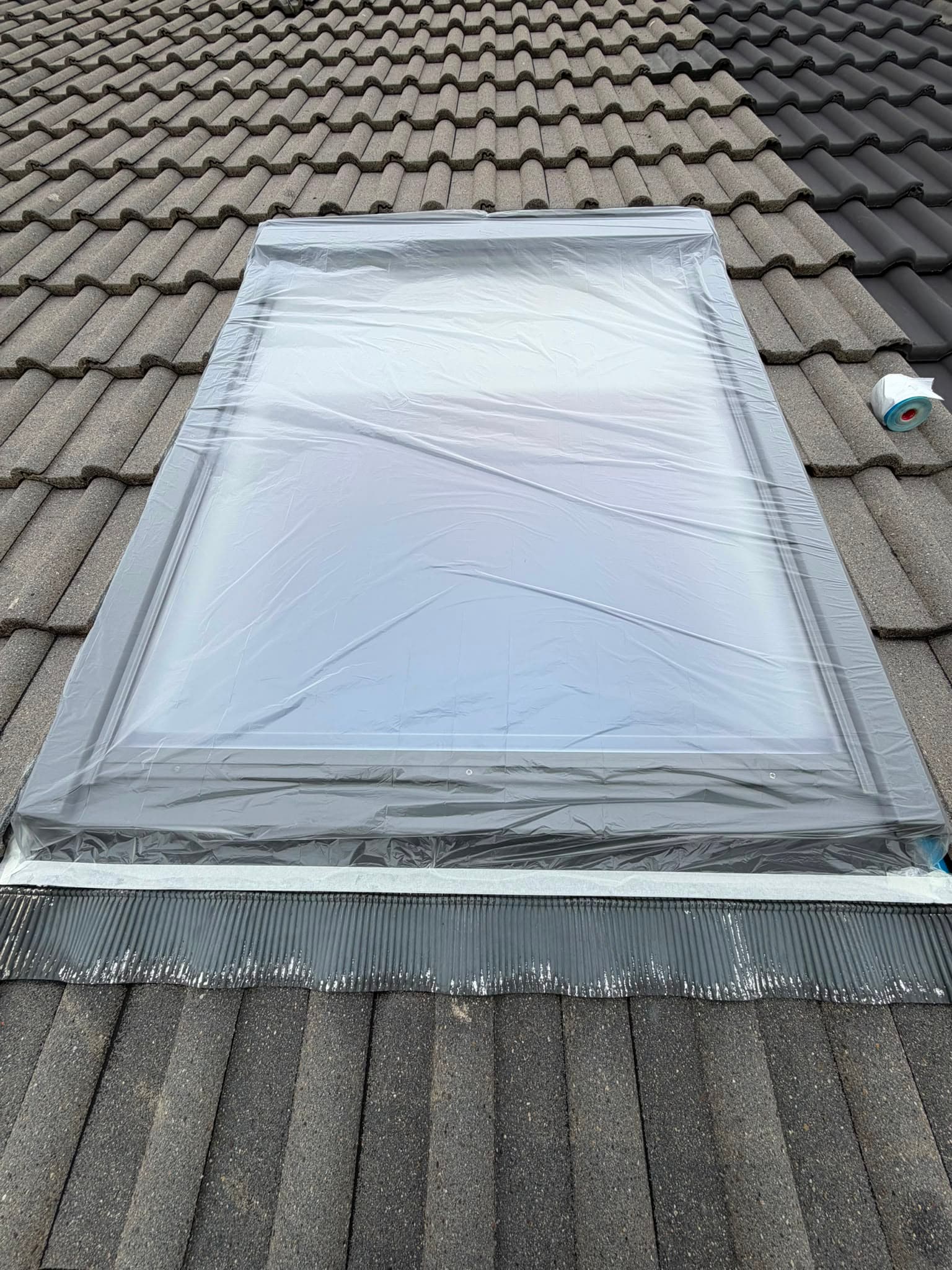 Mit Schutzfolie abgedecktes Dachfenster und abgeklebte Randbereiche vor der Beschichtung.